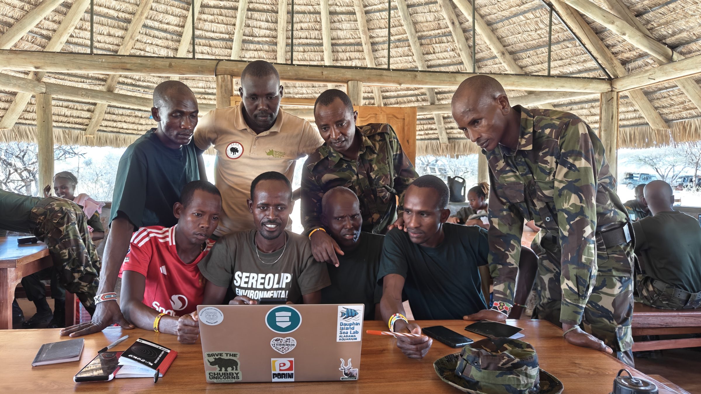 Rangers and Wildlife Health Watch staff gathered around a laptop reviewing wildlife health reports