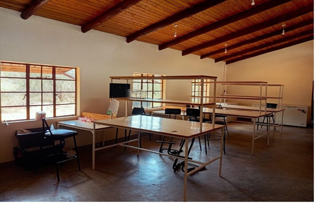 Dry lab with long worktables, chairs and metal shelving under a timber ceiling