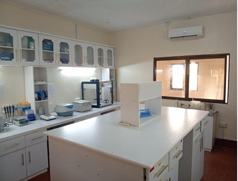 Molecular genomics lab at Mpala with a central white bench, benchtop instruments and glass-fronted storage cabinets